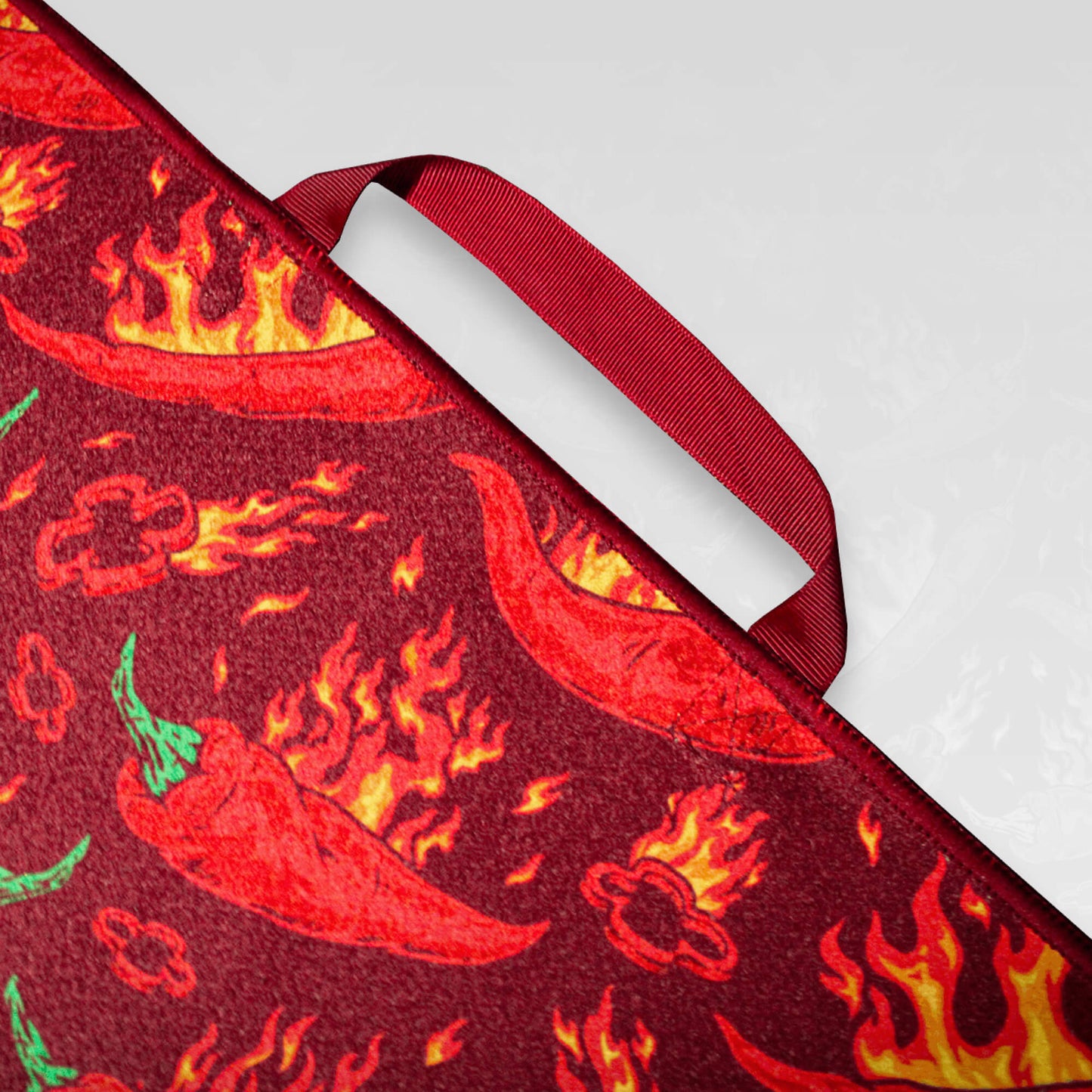 A close up of the handle of a flaming chilli pepper patterned microfibre golf towel