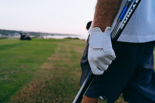 Close-up of a golfer's gloved hand holding a club on a beautiful golf course.